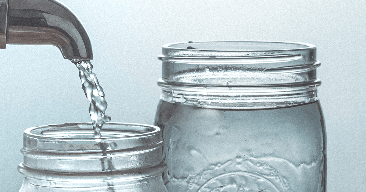 The tops of two mason jars. On the left, clean water flows from a tap into one of the jars. The other jar is full of clean water.